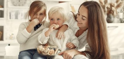 Mother and kids enjoying cookies in a warm, cozy kitchen setting.