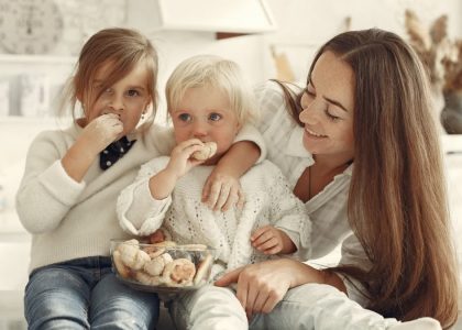 Mother and kids enjoying cookies in a warm, cozy kitchen setting.